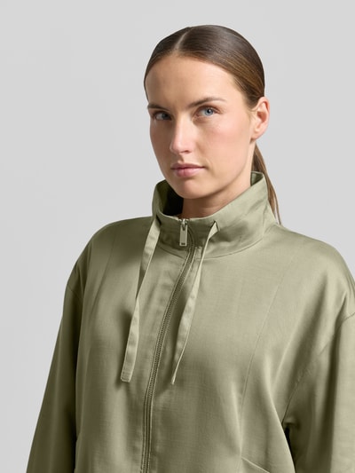 Frauenmodel trägt Jacke aus Lyocell-Baumwoll-Mix Modell 'Jarusa' von OPUS in Olivgrün, Stehkragen, Reißverschluss, Nahaufnahme Oberkörper.