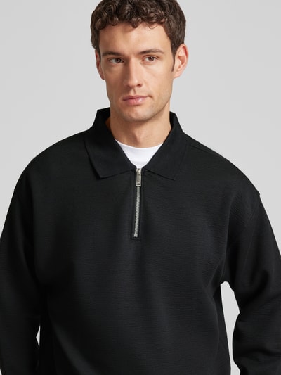 Męski model nosi Sweatshirt mit Polokragen und Reißverschluss od CK Calvin Klein, czarny, faktura crinkle crepe, relaxed fit, zbliżenie na górę ciała.
