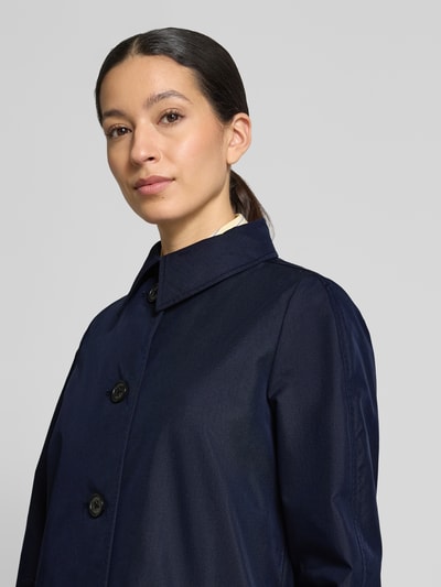 Vrouwenmodel draagt Regular Fit Trenchcoat aus Baumwoll-Mix van s.Oliver RED LABEL in effen donkerblauw katoen twill, knoopsluiting, kraag, zijzakken, labelapplicatie, rugpas, detailopname bovenlichaam