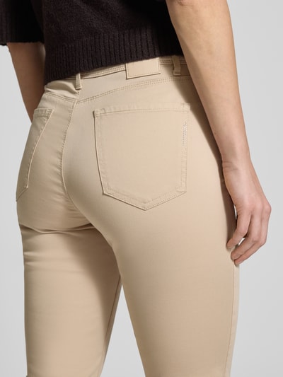 Frauenmodel trägt Flared Fit Jeans mit Lyocell-Anteil Modell 'Mary' von Brax, beigefarbener Baumwoll-Mix, 5-Pocket-Design, Nahaufnahme Rückansicht.