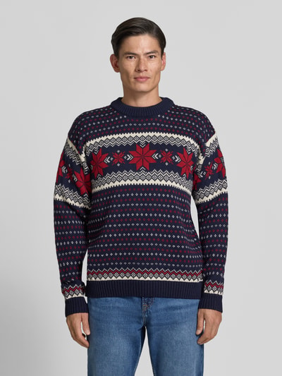 Männermodel trägt Regular Fit Wollpullover in Strick-Optik Modell 'Egersund' von Dale of Norway in Blau-Rot-Weiß, reine Wolle, Ganzkörperansicht von vorne.