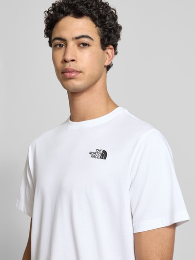 Männermodel trägt Regular Fit T-Shirt aus Baumwoll-Mix Modell 'VERTICAL' von The North Face, weiß mit Label-Print, Nahaufnahme Oberkörper. Herren T-Shirt, Rundhalsausschnitt, Rückenlänge bei Größe M 71 cm.