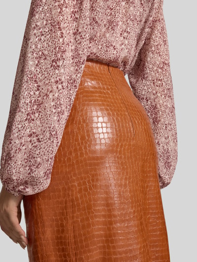 Frauenmodel trägt Midirock in Leder-Optik mit Gehschlitz von Jake*s Collection, cognacfarben, strukturierte Oberfläche, Detailaufnahme Rückansicht. Gerader Schnitt, Reißverschluss, Bundweite 40 cm, Länge 81 cm.