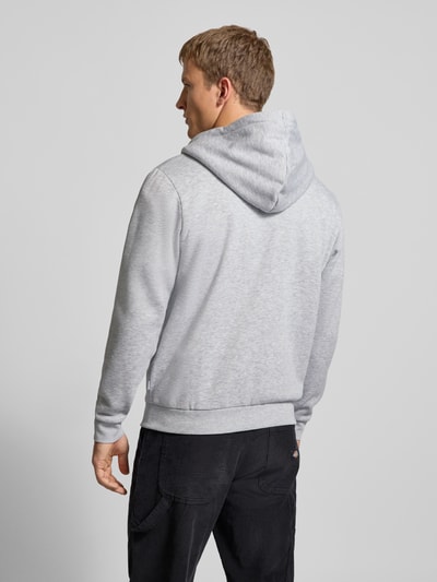 Männermodel trägt Sweatjacke mit Kapuze Modell 'BRADLEY' von Jack & Jones, grauer Baumwoll-Material-Mix, lockere Passform, Reißverschluss, Kängurutasche, Rückenlänge 74 cm, Ärmellänge 63 cm, Ganzkörperansicht Rückansicht.