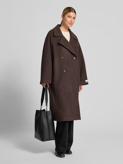 Vrouwenmodel draagt Relaxed Fit lange jas uit pure wol van ARMEDANGELS, donkerbruin, zware textuur, Ganzkörperansicht van voren.