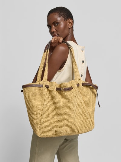 Frauenmodel trägt Bucket-Bag aus Bast von Tory Burch in Naturfarbe mit Drawstring-Verschluss, Tragehenkel und Innenfach, Ganzkörperansicht Rückansicht. Breite 52 cm, Länge 30 cm, Tiefe 15 cm.