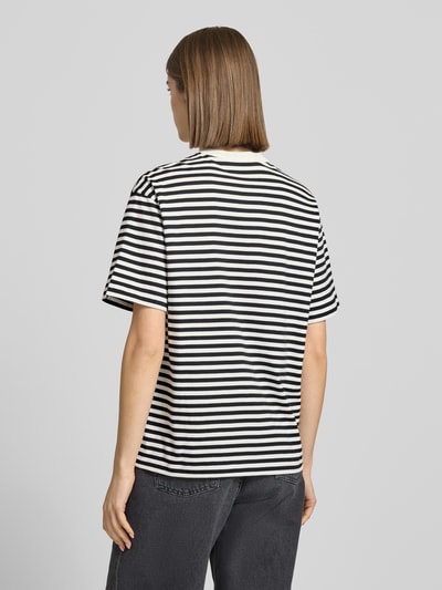Frauenmodel trägt T-Shirt mit Label-Stitching von Carhartt Work In Progress, schwarz-weiß gestreift, Baumwolle, relaxed fit, Ganzkörperansicht Rückansicht.