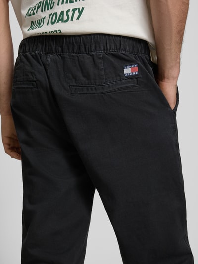 Männermodel trägt Straight Fit Jeans aus reiner Baumwolle von Tommy Jeans in schwarzer Denim-Optik mit elastischem Bundabschluss, Detailaufnahme Rückansicht.
