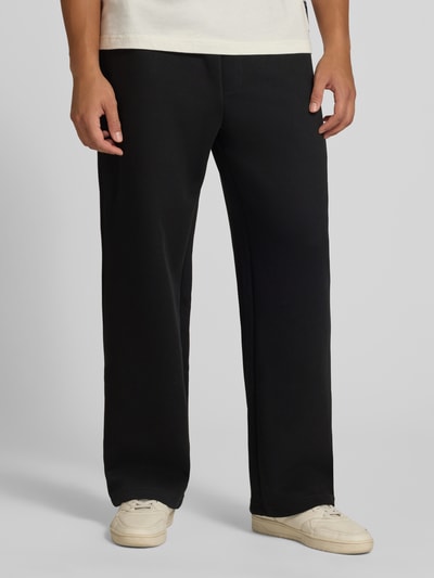 Männermodel trägt Straight Fit Sweatpants mit elastischem Bund von JACK & JONES in Schwarz, Baumwoll-Mix, Eingrifftaschen, Nahaufnahme Unterkörper.