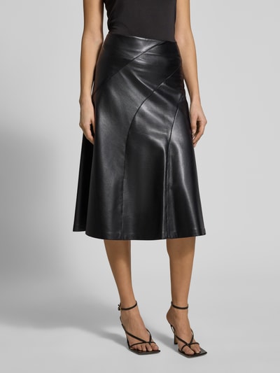 Frauenmodel trägt Ausgestellter Midi-Rock mit Reißverschluss Modell 'VICENA' von BOSS in schwarz glänzendem Kunstleder mit sichtbaren Nähten, Ganzkörperansicht von vorne.