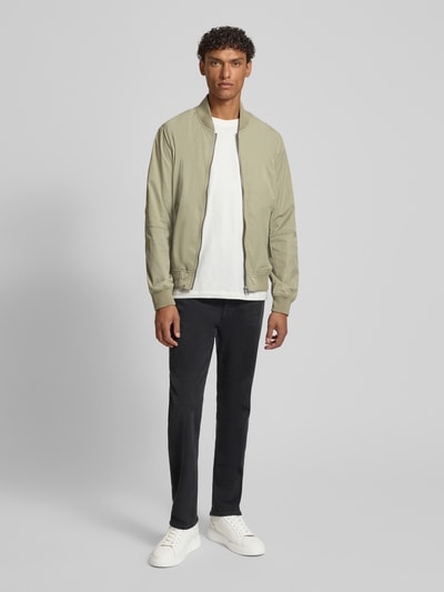 Männermodel trägt unifarbene Regular Fit Bomberjacke mit Stehkragen von s.Oliver RED LABEL, Reißverschluss, seitliche Pattentaschen, Ganzkörperansicht von vorne.
