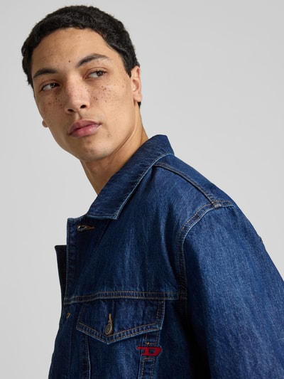 Männermodel trägt Jeansjacke mit Knopfleiste von Diesel aus Reine Baumwolle, Regular-Fit, Kentkragen, Label-Detail, Nahaufnahme Oberkörper.