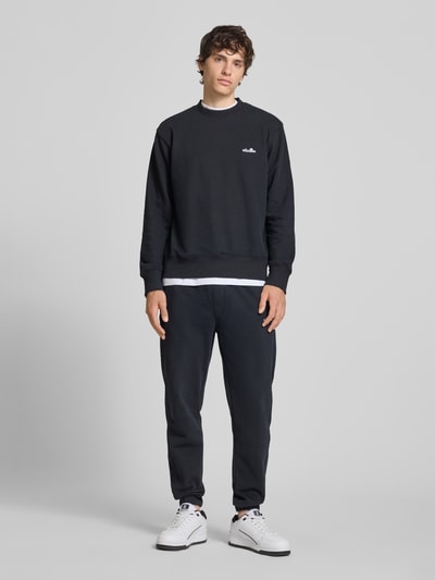 Männermodel trägt Sweatshirt mit Rundhalsausschnitt und Label-Stitching von Ellesse, Baumwoll-Mix, Regular-Fit, Ganzkörperansicht von vorne.