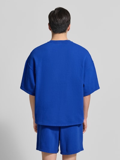 Männermodel trägt Herren T-Shirt mit Logo Modell 'PLIZZY' von American Vintage aus Reine Baumwolle, Relaxed-Fit, Rückenlänge 67 cm, Ganzkörperansicht Rückansicht.