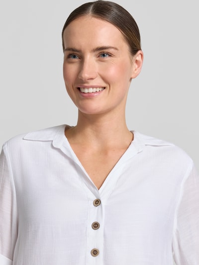 Frauenmodel trägt Blusenshirt mit Umlegekragen von Apricot aus weißem Viskose-Mix mit V-Ausschnitt und Knopfleiste, Nahaufnahme Oberkörper.