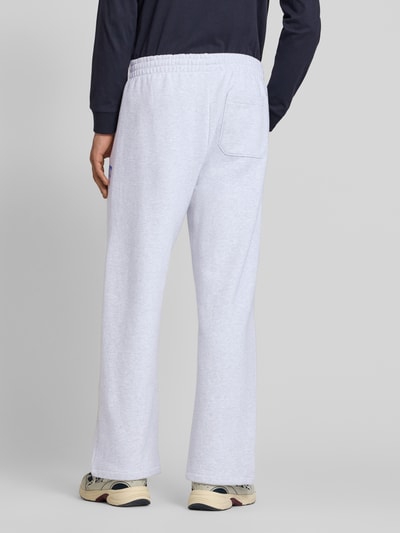 Männermodel trägt Sweatpants mit elastischem Bund und Label-Print von Carhartt Work In Progress in Hellgrau, Reine Baumwolle, Wide Leg, Längsnähte, Modell 'Pond Corps', Innenbeinlänge bei Größe M 72 cm, Ganzkörperansicht Rückansicht.