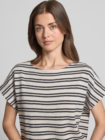 Kobiece model prezentuje damski t-shirt z mieszanki wiskozy, model 'Sostal' od OPUS, krój relaxed fit, okrągły dekolt, długość tyłu w rozmiarze 36: 54 cm, wzór w czarne i kremowe paski, tekstura dzianiny, zbliżenie na górną część ciała