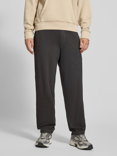 Männermodel trägt Relaxed Fit Sweathose aus reiner Baumwolle von G-Star RAW in Dunkelgrau mit elastischen Bündchen, Nahaufnahme Unterkörper.