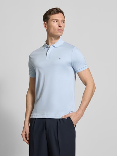 Męski model nosi Koszulka polo Regular Fit Poloshirt aus reiner Baumwolle Modell 'LIQUID COTTON' von Tommy Hilfiger, z efektem melanżu, krój regular fit, wyhaftowane logo, kołnierzyk polo, krótki rękaw, prążkowane zakończenie rękawów, wykończenie z bocznymi rozcięciami, bawełna, jasnoniebieski kolor, gładka tekstura. Ganzkörperansicht z przodu.
