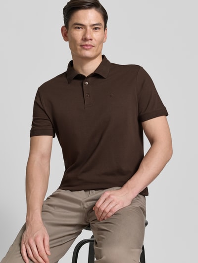 Męski model nosi Regular Fit Poloshirt mit Knopfleiste Modell 'Carlosjuan' von JOOP! Collection, bawełniany miks ze stretchem, krój regular fit, kołnierzyk polo, krótka listwa guzikowa, długość pleców w rozmiarze M: 69 cm, ciemnobrązowa koszulka, jasnobeżowe spodnie, gładka tekstura, całkowity widok z przodu.
