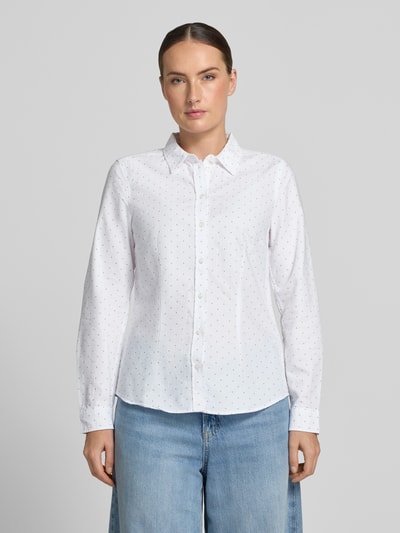Vrouwenmodel draagt Bluse mit Hemdblusenkragen und Knopfleiste van Christian Berg Woman van puur katoen, licht getailleerd model, afgeronde zoom, wit met kleine stippenmotief, knoopsluiting, ruglengte maat 36: 62 cm, mouwlengte maat 36: 59 cm, voorkant volledig zichtbaar, Ganzkörperansicht van voren.