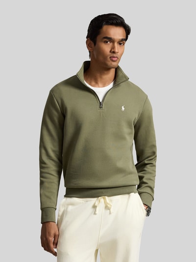 Männermodel trägt Relaxed Fit Troyer aus Baumwoll-Mix von Polo Ralph Lauren in Olivgrün, glatte Textur, Ganzkörperansicht von vorne.