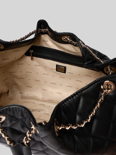 Produktfoto, Handtasche in Stepp-Optik Modell 'JULIET' von GUESS, schwarz mit goldfarbenem Kettenriemen, beige Innenfutter mit Logo, Hauptfach mit Tunnelzug, Detailaufnahme