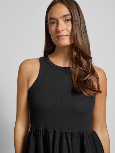 Frauenmodel trägt Midikleid mit Rundhalsausschnitt Modell 'MIRI' von YAS aus Baumwoll-Elasthan-Mix in Schwarz, Nahaufnahme Oberkörper. 
