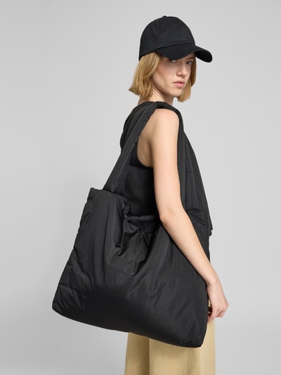 Młodzieżowe modelka nosi czarną Handtasche mit Logo-Detail Modell 'Mom' od STUDIO NOOS, materiał matowy, szeroki pasek, Szerokość w rozmiarze 1: 56 cm, długość: 45 cm, głębokość: 9 cm, długość paska: 72 cm, Ganzkörperansicht Rückansicht.