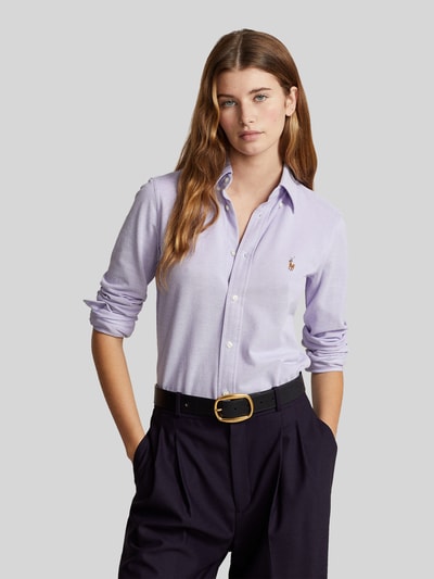 Kobiecy model nosi Hemdbluse mit Label-Stitching von Polo Ralph Lauren z czystej bawełny, krój slim fit, button-down kołnierzyk, listwa guzikowa, haftowane logo, długość tyłu w rozmiarze S: 67 cm, długość rękawa: 64 cm, jasnofioletowy kolor, gładka tekstura, widok na górną część ciała z przodu.