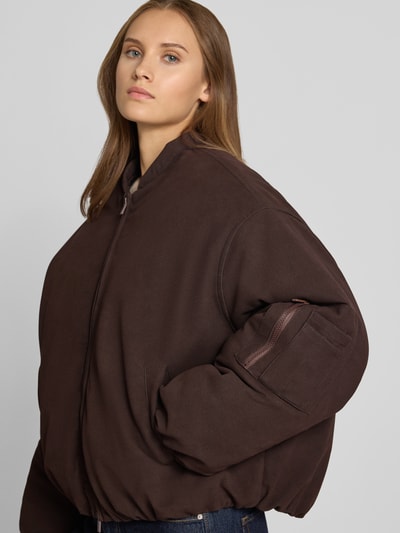 Frauenmodel trägt bomberka Bomberjacke mit Zweiwege-Reißverschluss von ANOTHER COTTON LAB, krój relaxed fit, stójka, wpuszczane kieszenie, kieszeń na rękawie zapinana na zamek błyskawiczny dwustronny, długość tyłu w rozmiarze S: 64 cm, szerokość ramion w rozmiarze S: 53 cm, szerokość klatki piersiowej w rozmiarze S: 60 cm, długość rękawów w rozmiarze S: 56 cm, ciemnobrązowy kolor, gładka tekstura, Ganzkörperansicht von vorne