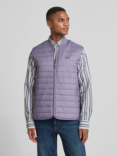 Männermodel trägt Steppweste mit Reißverschlusstaschen von CK Calvin Klein, glattes Material, Unifarbenes-Design, Label-Applikation, Gerade Passform, Stehkragen, Reißverschluss, Ganzkörperansicht von vorne.