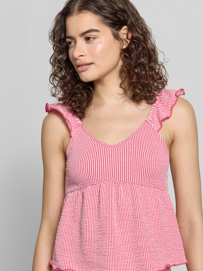 Frauenmodel trägt Regular Fit Trägertop aus Baumwoll-Mix Modell 'MISTY' von Only, Optik:Allover-Muster gestreift, Rüschen-Applikation, U-Ausschnitt, Seersucker-Struktur, Farbmix aus Weiß und Pink, elastisch, Nahaufnahme Oberkörper.