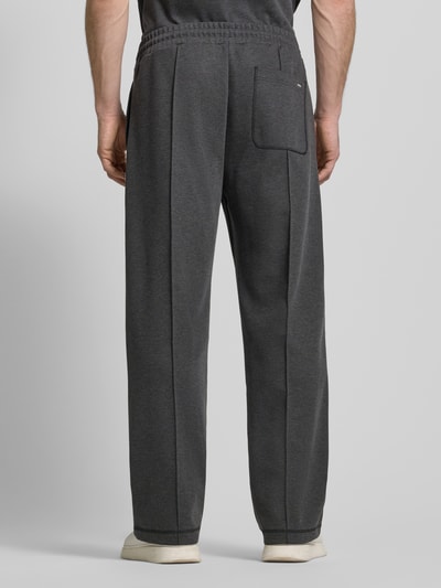 Mężczyzna ma na sobie spodnie dresowe Regular Fit Sweatpants aus Baumwoll-Mix Model 'DINETO' od HUGO, efekt: jednolity kolor, naszywka z logo, kanty, ściągacz z tunelem, wpuszczane kieszenie boczne, kieszeń z tyłu, wykończenie: dzianina dresowa, mieszanka bawełny; widok całej sylwetki z tyłu.
