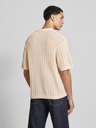 Mannelijk model draagt Slim Fit Poloshirt in Crochet-Optik van REVIEW, beige katoen, polokraag, halve mouw, logo detail, rugaanzicht fullbody.