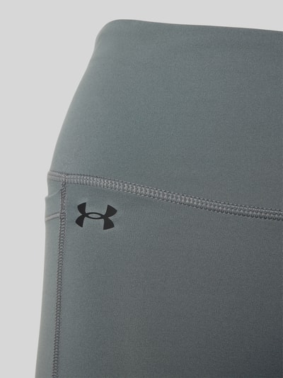 Frauenmodel trägt Flared Fit Leggins mit breitem Bund Modell 'Motion' von Under Armour aus Elastischer-Material-Mix, Logo-Print, Beintasche, Nahaufnahme Oberkörper.