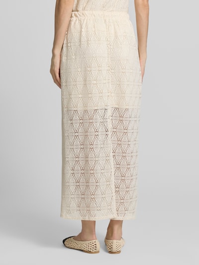 Frauenmodel trägt Leicht ausgestellter Midi-Rock aus Spitze mit elastischem Bund Modell 'MAYA' von Vero Moda, cremefarben mit geometrischer Spitzenstruktur, unifarben, mittellang, transparenter Spitzensaum mit blickdichtem Unterrock, Gehschlitz und elastischer Bund, Ganzkörperansicht Rückansicht.