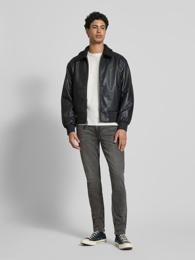 Männermodel trägt Slim Fit Jeans mit Label-Patch Modell 'HEARST' von Calvin Klein Jeans, grauer Used-Look, Ganzkörperansicht von vorne. Baumwoll-Elasthan-Mix, 5-Pocket-Design, sichtbarer Knopf- und Reißverschluss, Bundweite 40 cm, Innenbeinlänge 80 cm.