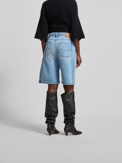 Frauenmodel trägt Relaxed Fit Jeansshorts aus Baumwolle von Diesel in hellem Blau mit Destroyed-Look, 5-Pocket-Design, Ganzkörperansicht Rückansicht.