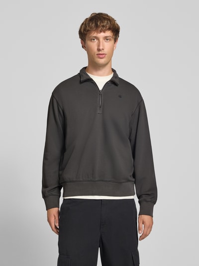 Männermodel trägt Regular Fit Sweatshirt aus reiner Baumwolle von G-Star RAW in Dunkelgrau, glatte Textur, Ganzkörperansicht von vorne.