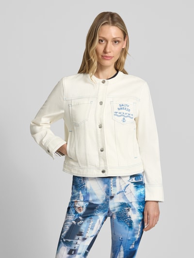 Frauenmodel trägt Jeansjacke mit Motiv- und Statement-Stitching von Marc Cain in Offwhite, sichtbare Nähte, Knopfleiste, Brusttasche, Baumwoll-Mix mit Stretch-Anteil, Gerader-Schnitt, Rundhalsausschnitt, Eingrifftaschen, Rückenlänge bei Größe 36: 50 cm, Schulterbreite 42 cm, Brustweite 46 cm, Ärmellänge 49 cm, Ganzkörperansicht von vorne.