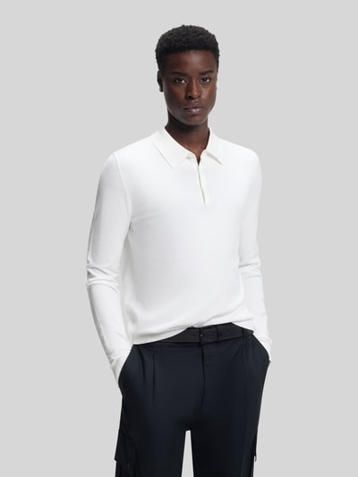 Männermodel trägt Slim Fit Strick-Poloshirt aus Viskose-Mix Modell 'SAN PIPPO-CV' von HUGO in Weiß, feiner Rippstrick, Ganzkörperansicht von vorne.