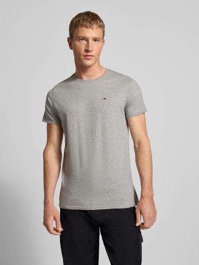 Męski model nosi T-shirt in Melange-Optik od Tommy Jeans z bawełny, prosty krój, okrągły dekolt, wyhaftowane logo, efekt melanżu, długość tyłu 68 cm, rozmiar M, całkowita sylwetka z przodu.