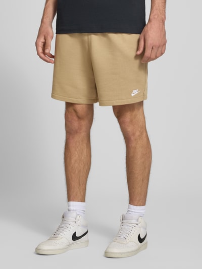 Männermodel trägt Regular Fit Sweatshorts aus Baumwoll-Mix von Nike in Beige, glatte Textur, lockere Passform, Ganzkörperansicht von vorne, Herren Sweatshorts von Nike.