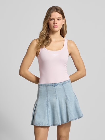 Frauenmodel trägt Tanktop in Ripp-Optik mit Label-Stitching von Guess Jeans aus Baumwoll-Elasthan-Mix, Slim-Fit, hellrosa, Ganzkörperansicht von vorne.