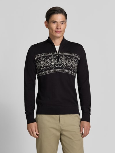 Männermodel trägt Wollpullover mit Label-Patch Modell 'Liaset' von Dale of Norway, schwarz mit grauem Muster, Nahaufnahme Oberkörper. Reine Wolle, gerader Schnitt, Troyer-Kragen, Rückenlänge 66 cm, Ärmellänge 69 cm.