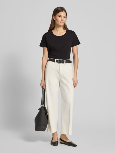 Frauenmodel trägt T-Shirt aus reiner Baumwolle von ARMANI EXCHANGE in Schwarz mit Strasssteinbesatz, gerader Schnitt, Nahaufnahme Ganzkörperansicht von vorne.