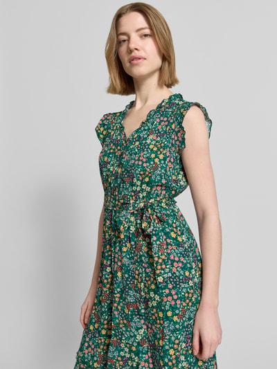 Frauenmodel trägt Minikleid aus reiner Viskose mit floralem Allover-Print von Apricot, taillierte Passform, V-Ausschnitt, Ganzkörperansicht von vorne.