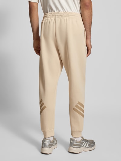 Mannenmodel draagt Regular Fit Sweathose met Logoprint van adidas Sportswear, katoenmix, regular fit, elastische band met tunnelkoord, elastische boorden, logoprint, binnenbeenlengte bij maat M 71 cm, geheel van achteren.