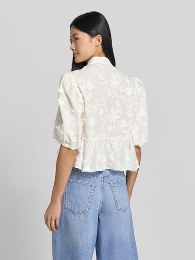 Frauenmodel trägt Regular Fit Bluse mit V-Ausschnitt Modell 'CAPUCHIN' von MANGO aus reiner Baumwolle, Stickdetails, Rückansicht.
